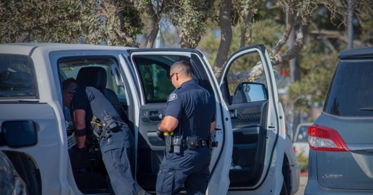 Two police officers conduct a search of a suspect's vehicle