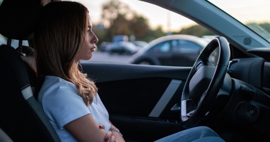 Woman sitting in car with arms crossed